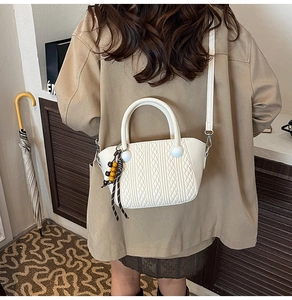 Detailed view of a white woven texture handbag featuring decorative wooden beads