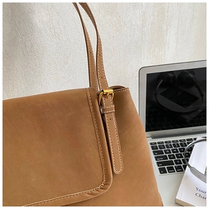 Détail du sac cabas vintage en cuir marron avec surpiqûres blanches et accessoires