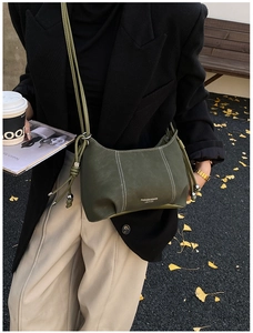 Detail of dark green leather handbag featuring white fashion text and contrast stitching