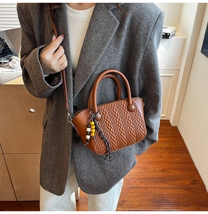 Detail of a brown quilted bucket bag featuring unique bead charms and a shoulder strap