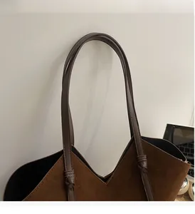 Detail of durable knotted handle and V-shaped opening on a vintage brown suede tote bag