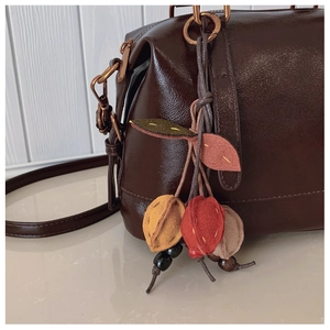 Detailansicht der braunen Boston-Handtasche mit farbenfrohem, handgemachtem Fruchtanhänger