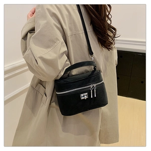 Détail d'un sac à main carré en cuir mat noir avec fermoir argenté et bandoulière