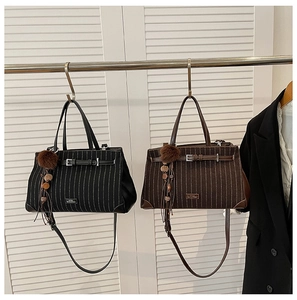 Detailed view of striped tote bags in black and brown with plush charm accessories