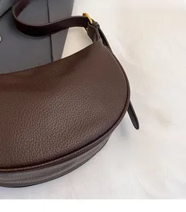 Close-up of brown litchi pattern leather hobo bag with gold buckle detail