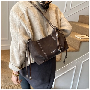Detail of dark brown leather handbag with contrast stitching and drawstrings with pendants