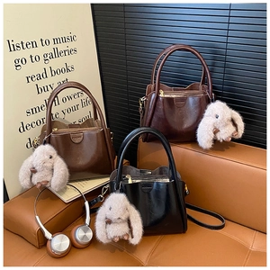 Detailed view of glossy leather handbags in brown and black with plush rabbit charms