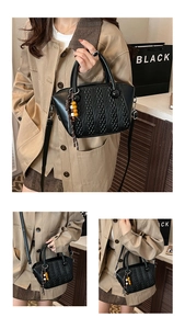 Detail view of black woven bucket bag with wood bead charm and adjustable strap