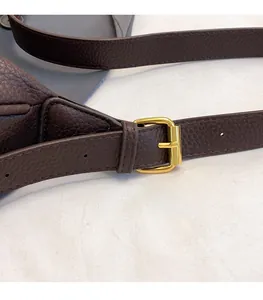 Detail of adjustable dark brown pebble leather shoulder strap with gold metal buckle