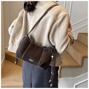 Detail of dark brown leather handbag featuring contrast white stitching and side drawstring