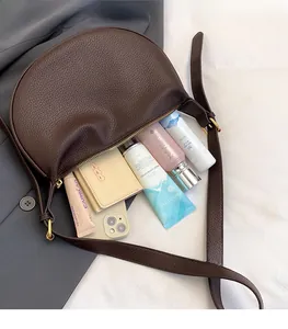 Detail of spacious interior in dark brown lychee leather crescent bag for essentials