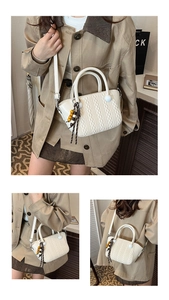 Close-up of woven texture detail on cream white faux leather handbag with wooden bead tassel