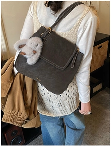 Détail du sac à bandoulière marron mat avec surpiqûres blanches et pendentif lapin peluche