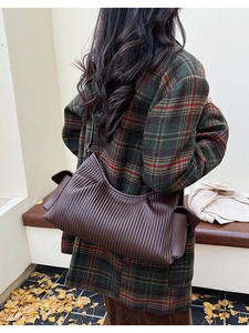 Detail of dark brown pleated leather shoulder bag with accordion texture for women