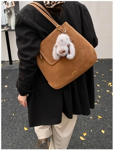 Sac bandoulière en daim marron avec pendentif lapin gris dans un décor d'automne