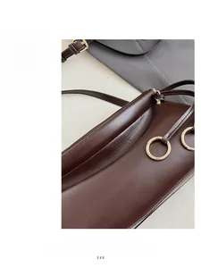 Dettaglio borsa baguette in pelle marrone scuro con anello in metallo e cuciture fini