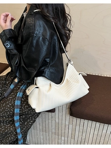 Detail of off-white hobo bag showing fine vertical pleats and decorative side buckles