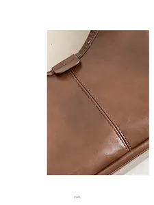 Detailed close-up showing the fine stitching and oil wax leather texture of the brown tote bag