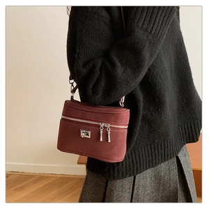 Sac bandoulière rectangulaire bordeaux porté avec une jupe plissée grise et un tricot noir