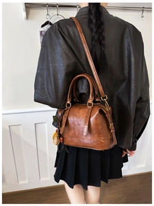 Detail der braunen Vintage-Lederhandtasche mit Blattanhänger, getragen von einem Model