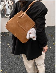 Détail du sac à épaule rétro en cuir marron avec breloque lapin en peluche et logo