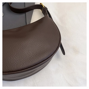 Detailed macro view of dark brown pebbled leather texture and stitching on crossbody bag