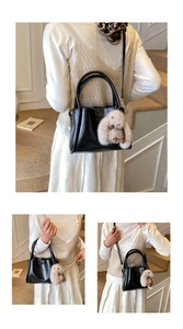 Detail of black glossy leather handbag with bunny charm and detachable strap accessory