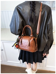 Retro-braune Boston-Tasche mit Ledertextur und Quaste, präsentiert an einem Model