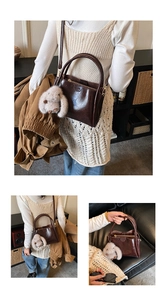 Detail of vintage oil wax leather handbag with plush bunny charm and crossbody strap