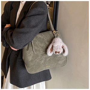 Détail du sac cabas gris-vert avec texture vintage et breloque lapin en peluche