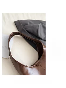 Close-up of dark brown leather shoulder bag showing strap stitching and texture