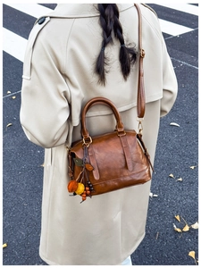 Braune Vintage-Boston-Tasche mit Blattanhänger in einer herbstlichen Straßenszene