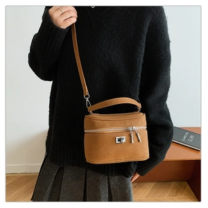Sac bandoulière vintage marron avec détails argentés porté par un mannequin en intérieur