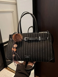 Chic oversized striped tote bag with leather handles and decorative tassel hanging