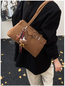 Gros plan du sac bandoulière en cuir caramel avec boucle noeud et pendentif d'ours