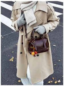 Detailansicht einer dunkelbraunen Boston Bag mit bunten Fruchtanhängern und Ledertextur