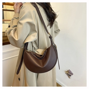 Detail of dark brown pebble leather hobo bag with adjustable strap on a shoulder