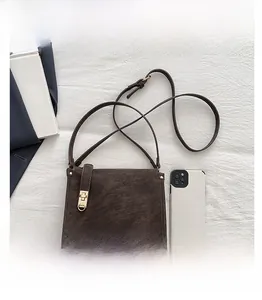 Detail view of vintage dark brown crossbody bag featuring gold turn-lock and studs