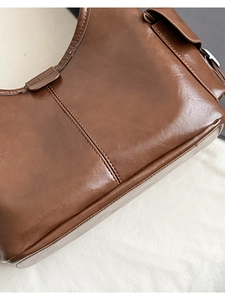 Close-up of vintage brown oil wax leather texture and parallel stitching on tote bag