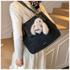 Détail d'un cabas en daim noir avec breloque lapin en peluche et logo doré