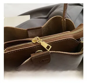Detailed close-up of brown leather bag with gold hardware and branded embossing