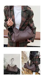 Detail showing deep brown pleated leather texture and unique side ear design on tote bag