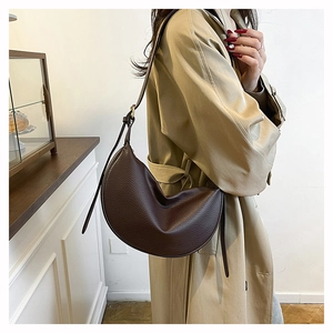 Detail of soft dark brown leather shoulder bag with textured lychee grain and adjustable strap