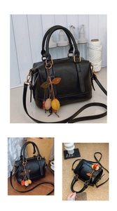 Detail der schwarzen Boston Bag mit buntem Blattanhänger und goldenen Beschlägen