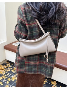 Dettaglio della borsa baguette beige con chiusura a pieghe e dettaglio ad anello in metallo