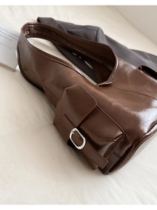 Detailed view of dark brown oil wax leather shoulder bag with vintage silver buckle pocket