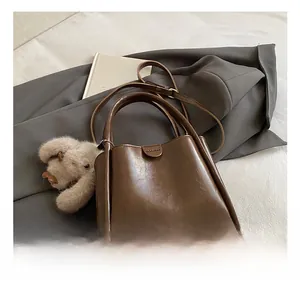 Detail of brown leather tote bag with round hardware and plush bunny charm accessory
