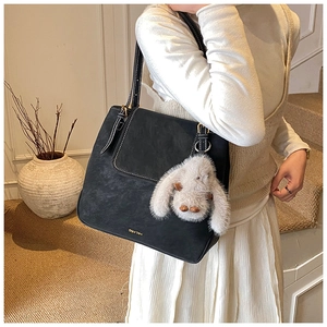 Détail d'un sac seau noir avec surpiqûres blanches et pendentif lapin en peluche doux