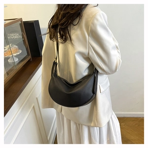 Detail of black pebbled leather half-moon bag with adjustable strap and metal zipper