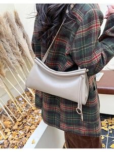 Dettaglio della borsa baguette in pelle beige con pieghe e anello in metallo dorato